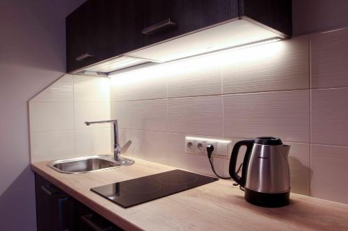 a kitchen with a sink and a kettle on a counter at Mēness Apartamenti in Cēsis