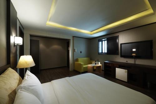ソウルにあるホテル ノブレス イェオサムのベッド1台、薄型テレビが備わるホテルルームです。