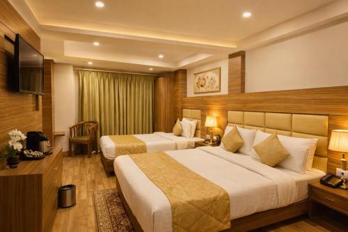 Una habitación de hotel con dos camas y un televisor. en Hotel Bella Vista Near Drc Parking, en Darjeeling