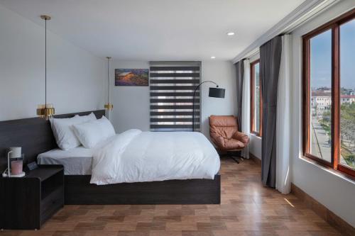 a bedroom with a bed and a chair and windows at Monaco Hotel in Sapa