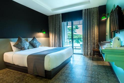 a bedroom with a large bed and a large window at Chiangkhong Teak Garden Riverfront Onsen Hotel- SHA Extra Plus in Chiang Khong