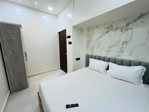 a bedroom with a white bed and a wall at Hotel O Aundh Homtel in Dāpuri