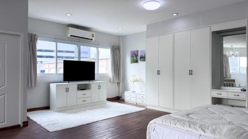 a white bedroom with a bed and a flat screen tv at Blissful Heaven Residence at BTS Phromphong Emdistrict Shopping Area in Bangkok