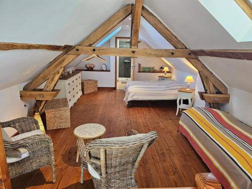 Gîte Le p'tit nid de Montachon, Saulieu, Morvan في Saint-Didier: غرفة نوم في العلية بها سرير وكراسي من الخيزران