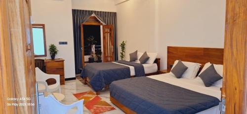 een hotelkamer met twee bedden en een spiegel bij Green inn Trinco in Uppuveli