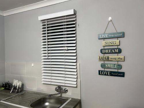 a kitchen with a sink and a window with signs at Awezi Overnight in Coldstream