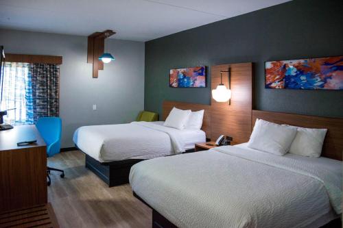 a hotel room with two beds and a desk at La Quinta Inn & Suites by Wyndham Fayetteville I-95 in Fayetteville