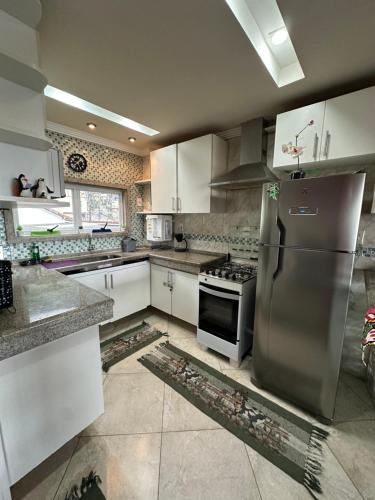 eine Küche mit weißen Schränken und einem Edelstahlkühlschrank in der Unterkunft Casa com Belas vistas - Muriqui in Mangaratiba