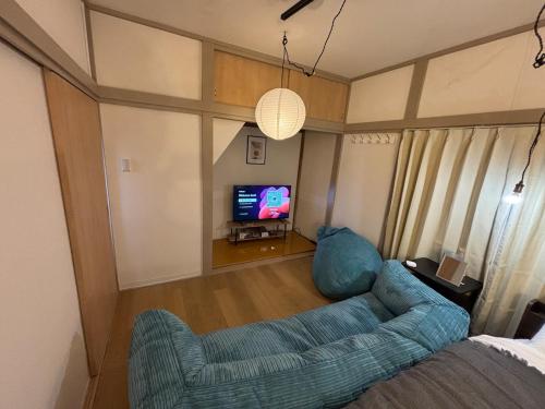 a living room with a blue couch and a tv at Tokyo Nest Ohana in Tokyo