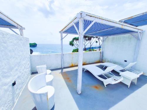 a balcony with white chairs and tables and the ocean at Jungwok Blue Ocean Resort in Ngandong
