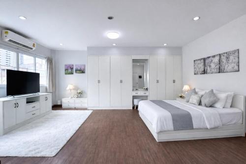 a white bedroom with a bed and a flat screen tv at Blissful Heaven Residence at BTS Phromphong Emdistrict Shopping Area in Bangkok