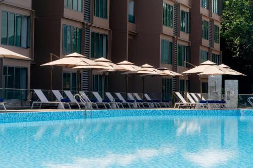a hotel swimming pool with chairs and umbrellas at Wyndham Garden Phuket Kamala in Kamala Beach