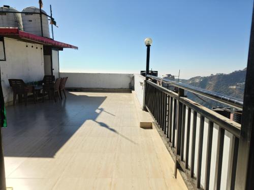 ein Balkon mit Stühlen und einem Tisch auf einem Gebäude in der Unterkunft Shiv Guest House in Masuri