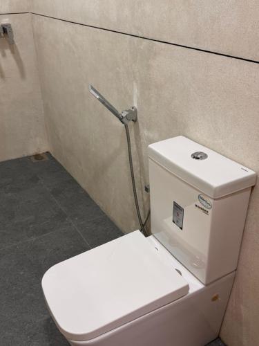 un aseo blanco sentado en un baño con pared en Leafy Haven Villa, en Liyanegoda