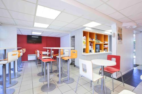 a restaurant with tables and chairs and a tv at Premiere Classe La Rochelle Nord - Puilboreau in Puilboreau