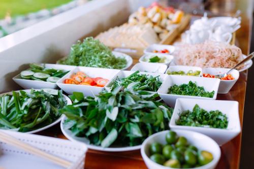 een tafel met kommen groenten en andere voedingsmiddelen bij Charm Hon Rom Villas Resort in Ấp Long Sơn