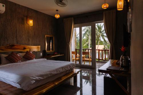Ấp Long SơnCharm Hon Rom Villas Resort的一间带大床的卧室和一个阳台