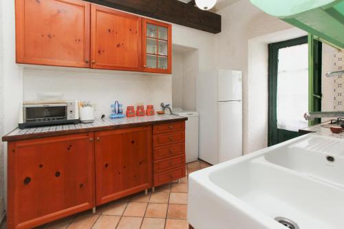 a kitchen with wooden cabinets and a white refrigerator at Villa Eleanto in Cefalù