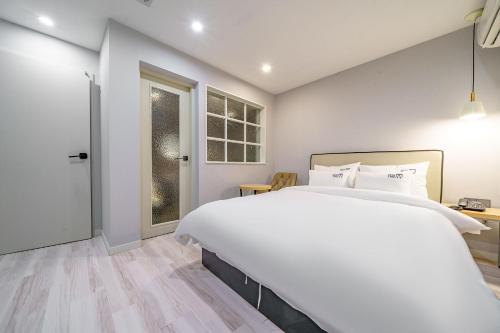 a white bedroom with a large bed and a window at 광안비치호텔더엠 in Kwangan-dong