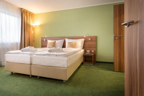 a bedroom with a large bed and a window at Kurhotel Pyramide Sibyllenbad in Neualbenreuth