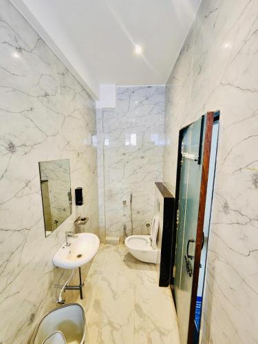 a bathroom with a sink and a toilet and a mirror at GOKUL Hotel in Maheshwar