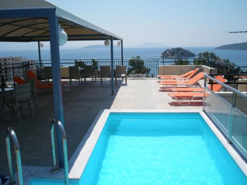 una piscina con sillas, una mesa y el océano en Alonia Studios & Maisonettes en Tolo
