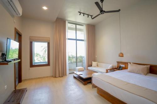 a bedroom with a bed and a couch and a tv at Emerald Resort Hikkaduwa in Hikkaduwa