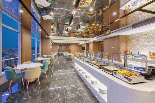 un restaurant avec une ligne de buffet avec des tables et des chaises dans l'établissement Dalian Zhongshan Square Seaview Meilun Hotel, à Dalian
