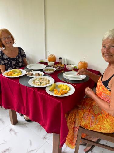 two women sitting at a table with plates of food at Stanley Villa One in Induruwa