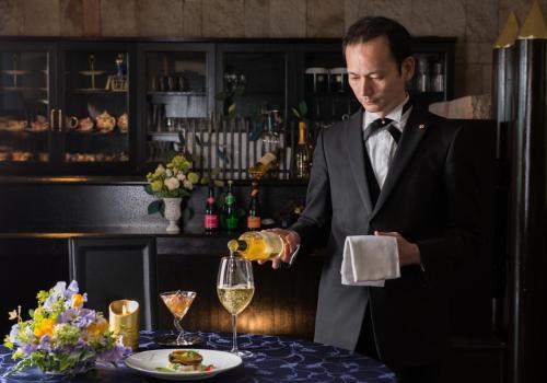 a man in a suit pouring a glass of wine at Hana Irodori no Yado Kayuu in Taiji
