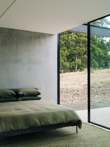 a bedroom with a bed and a large window at Triptych - The Blunt House in Koonya