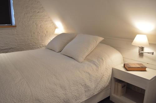 a bedroom with a white bed with a night stand at De Waterzooi Lodge in Ghent