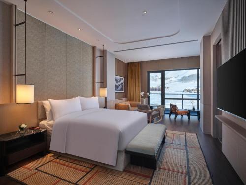 a bedroom with a large white bed and a living room at Conrad Altay Hemu in K'u-mu