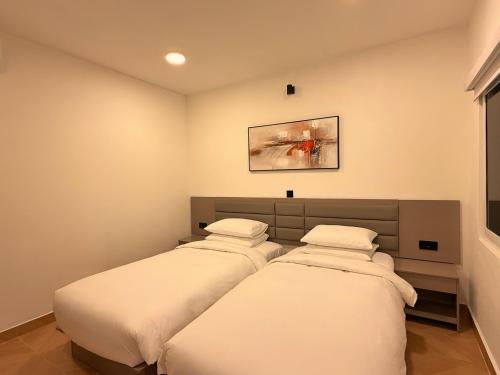a bedroom with three beds and a picture on the wall at Manta Beach Retreat in Hikahera