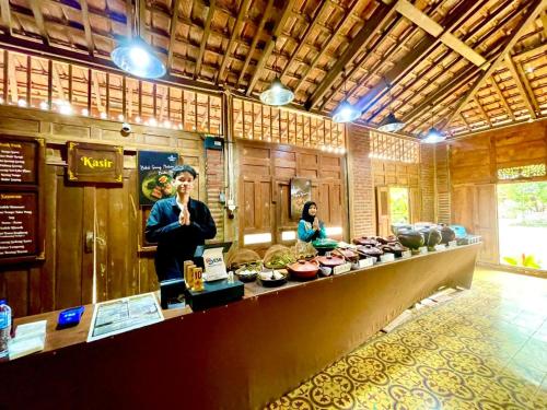 um homem parado atrás de um balcão num restaurante em Nglaras Resort Yogyakarta em Ngaglik