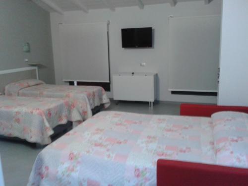 a room with two beds and a flat screen tv at Agriturismo La Sapienza in Monestirolo