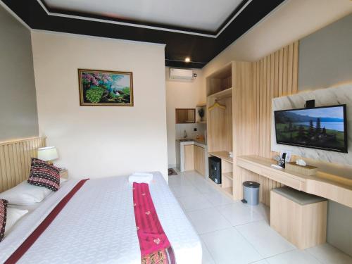 a bedroom with a bed and a flat screen tv at Surya Pandawa Homestay in Uluwatu