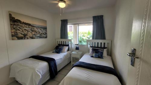 two beds in a room with a window at La Crete Sands no 3 in Uvongo Beach