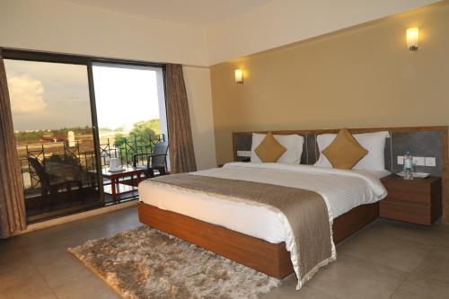 a bedroom with a large bed and a large window at VITS Kamats Resort, Silvassa in Silvassa