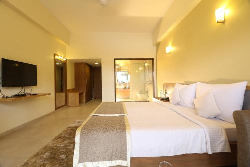 a bedroom with a large bed and a television at VITS Kamats Resort, Silvassa in Silvassa