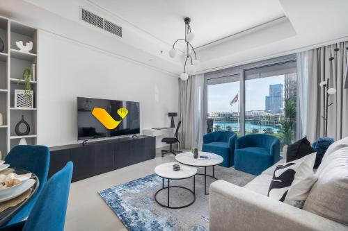 a living room with a couch and a tv at Vogue Vacation Homes, Downtown Opera Grand near Burj Khalifa and Dubai Mall, Two Bedroom Apartment with Large Balcony and Burj Khalifa view, Access to all Amenities in Dubai