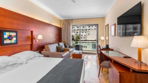 Una habitación de hotel con una cama grande y un escritorio. en Protur Roquetas Hotel & Spa, en Roquetas de Mar