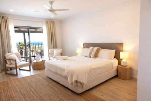 a white bedroom with a bed and a balcony at The African Reef in Geraldton