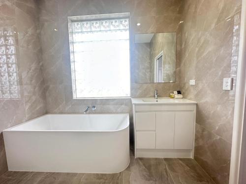 Un baño con bañera blanca y lavabo. en Puffers Inn, en Loganholme