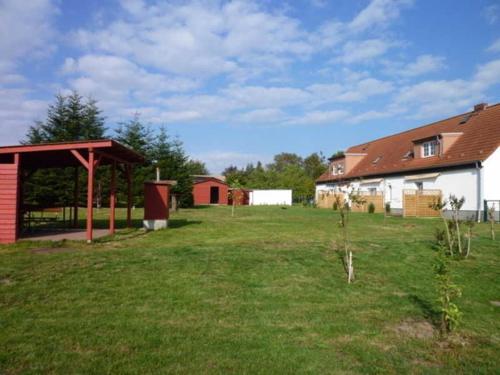 Un patio con una casa y un granero con un campo de hierba. en Ferienwohnungen Hohen Niendorf bei Kühlungsborn, en Hohen Niendorf