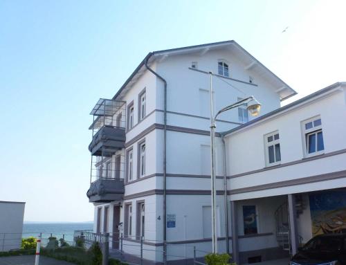 een wit gebouw met een straatlantaarn naast de oceaan bij Ferienwohnung Sassnitz mit Meerblick in Sassnitz