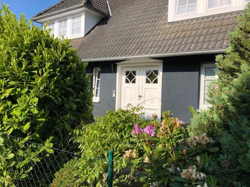 ein graues Haus mit einer weißen Tür und einigen Büschen in der Unterkunft Urlaub in Wieck in Wieck