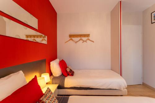 Un dormitorio con dos camas y una pared roja. en Chambre - Joubarbe, en Aroue