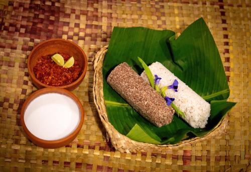Un plato de comida sobre una hoja de plátano con un tazón de leche. en Ayurveda Spring Of Life Resort, en Piliyandala