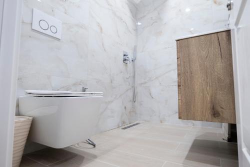 a white bathroom with a toilet and a shower at Centralin Apartotel in Tirana